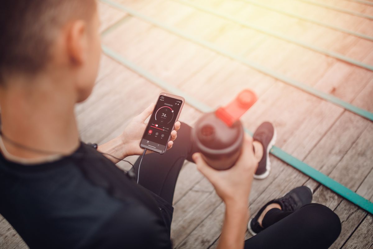 sportowiec trzymający butelkę wody i telefon