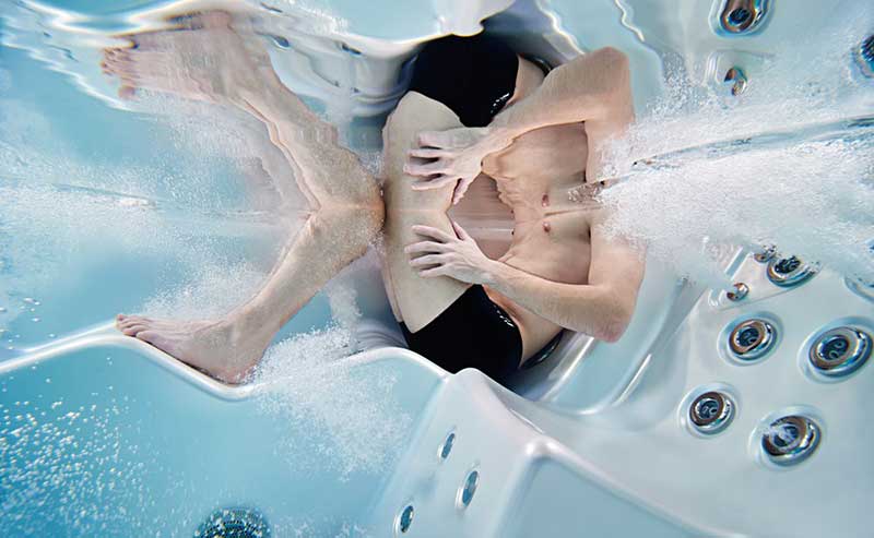 Kobieta relaksująca się na ergonomicznym leżaku w basenie spa USSPA z działającymi dyszami hydromasażowymi